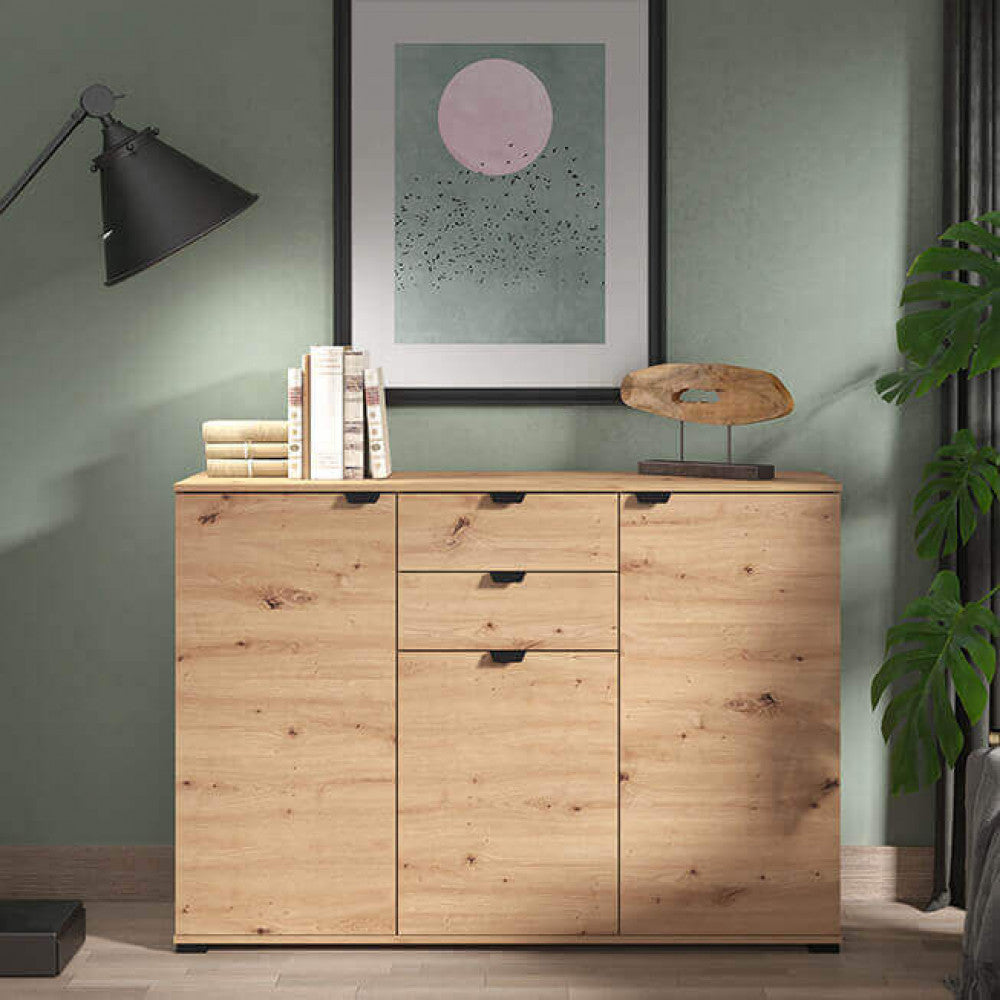 Credenza Duero posizionata contro una parete verde salvia, abbinata a una lampada da terra nera e decorazioni scultoree.