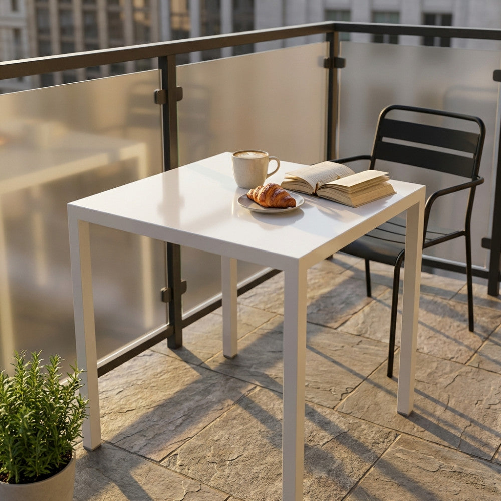 Tavolo da giardino quadrato in acciaio bianco allestito su un balcone moderno con colazione e libro.