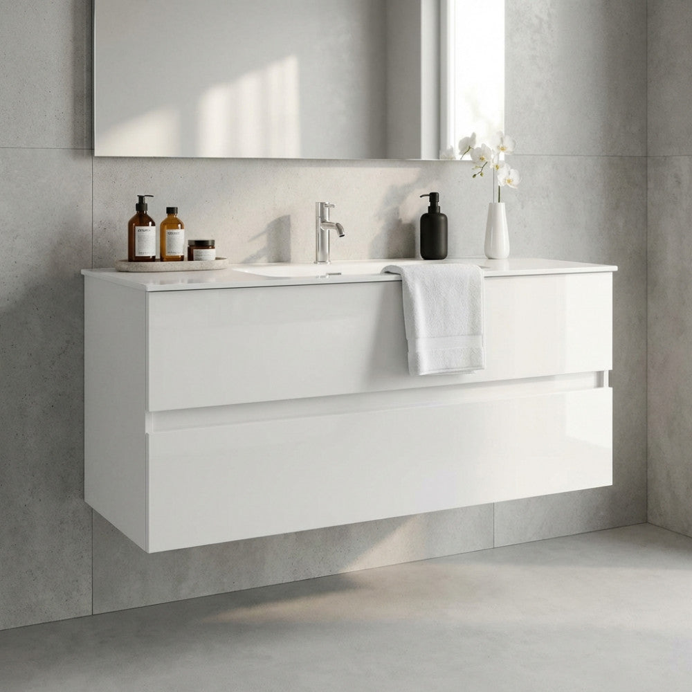 Vista frontale del mobile bagno sospeso Riccardo in bianco lucido, allestito con un asciugamano bianco, eleganti dispenser e una delicata orchidea in un ambiente moderno.