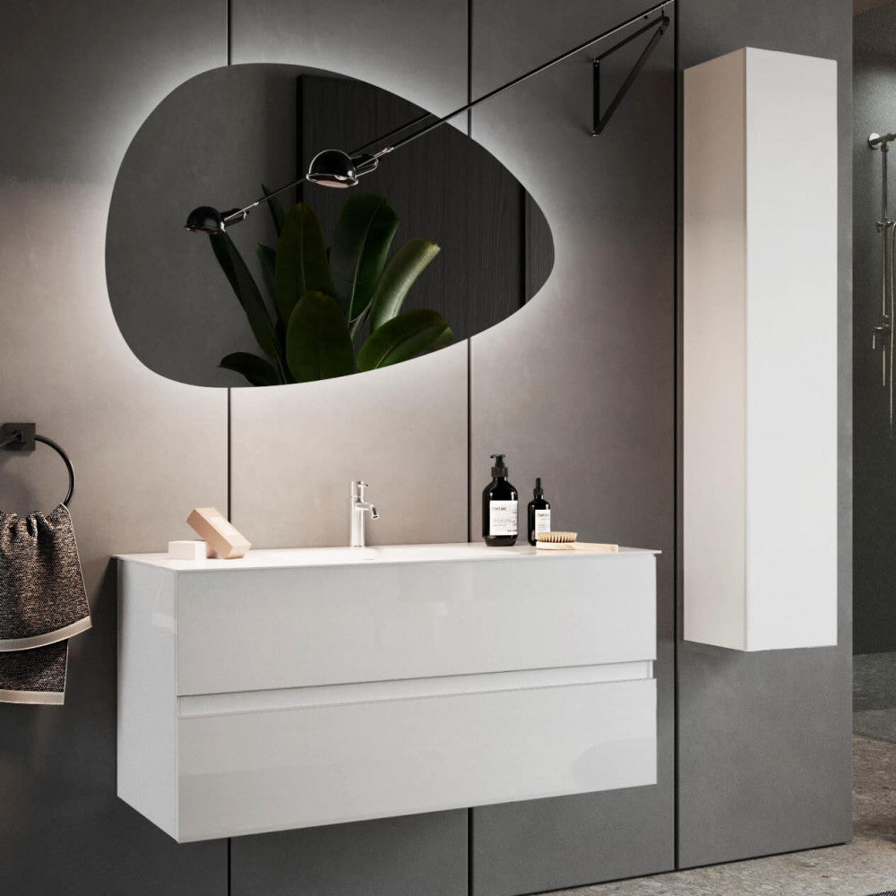 Sofisticato scatto ambientato del mobile sospeso abbinato a uno specchio asimmetrico illuminato, un'elegante lampada da parete e una colonna abbinata su pareti grigio scuro testurizzate.