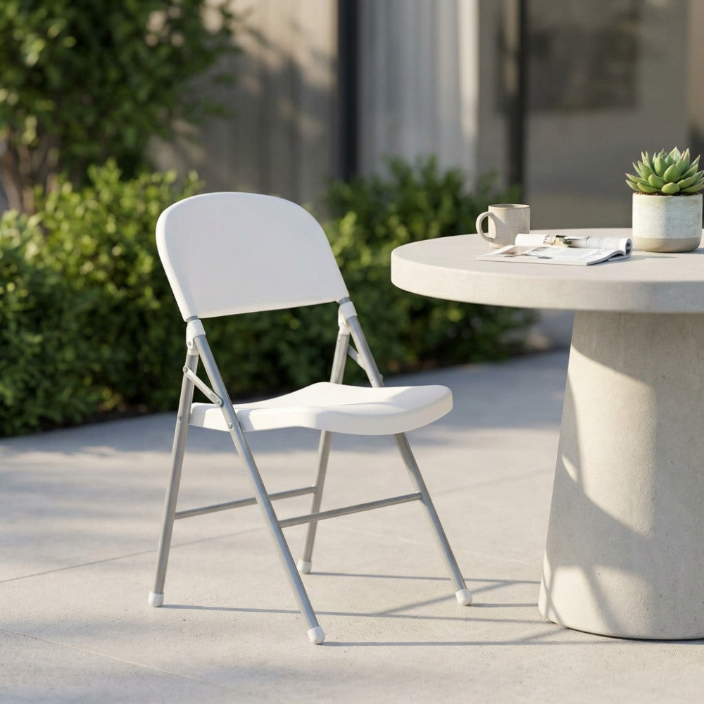Sedia pieghevole bianca minimalista MO806547 posizionata su un moderno patio in cemento accanto a un tavolo da pranzo scultoreo.