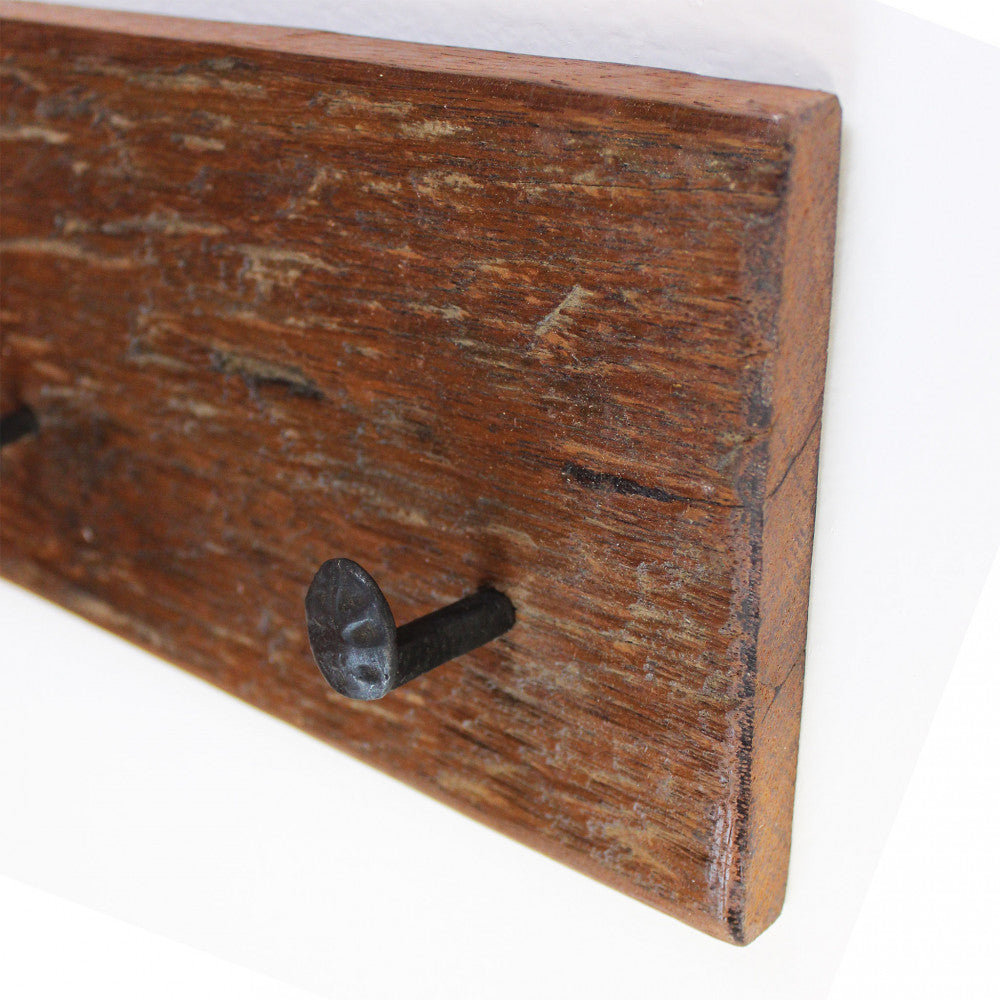 Angolazione laterale che mostra la texture ruvida del legno riciclato e la sporgenza dei ganci in ferro.