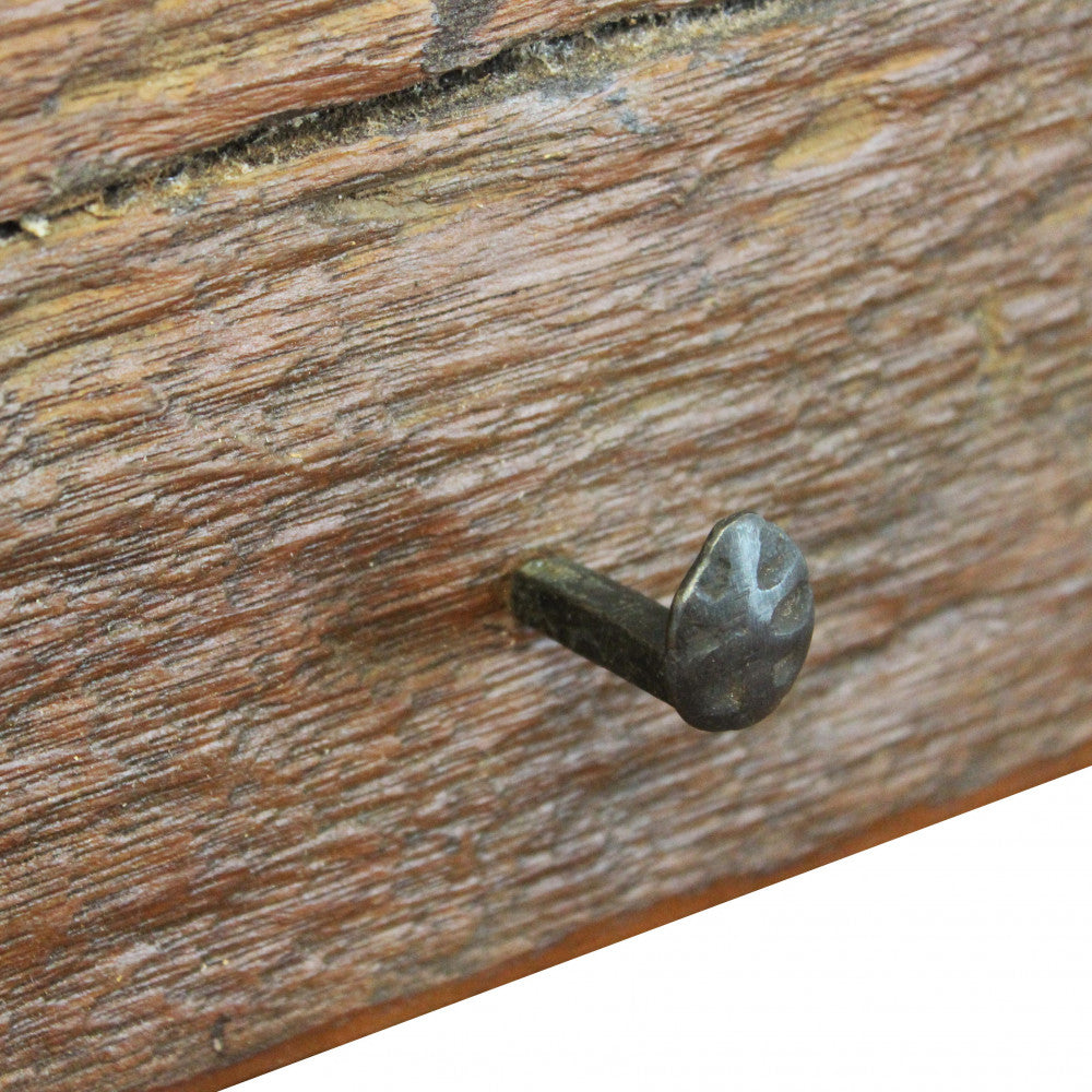 Dettaglio ravvicinato della superficie materica del legno riciclato e della testa del chiodo in ferro.