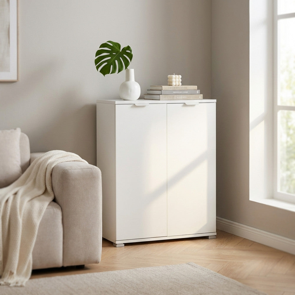 Armadietto a due ante bianco ambientato in un soggiorno luminoso con vaso decorativo.