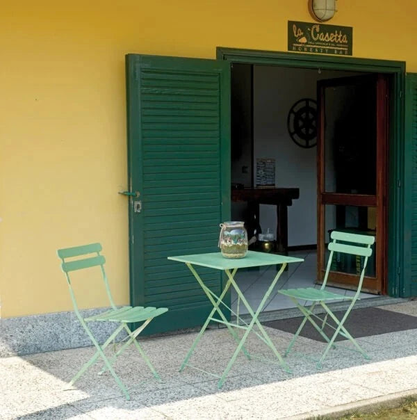 Sedia Bistro Pieghevole Verde in ferro verniciato antiruggine, design compatto per esterni, ambientata con tavolino