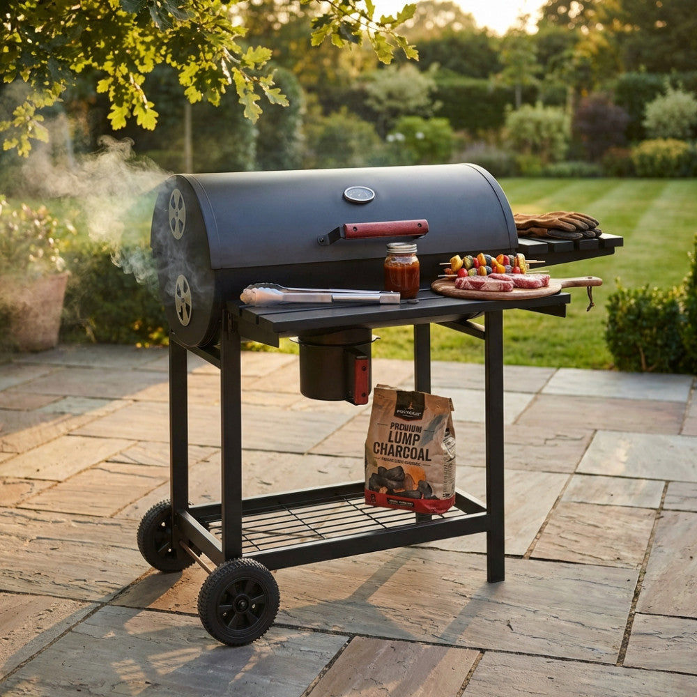 Barbecue a carbonella in acciaio nero in funzione su un patio in pietra, con fumo e carne in cottura.
