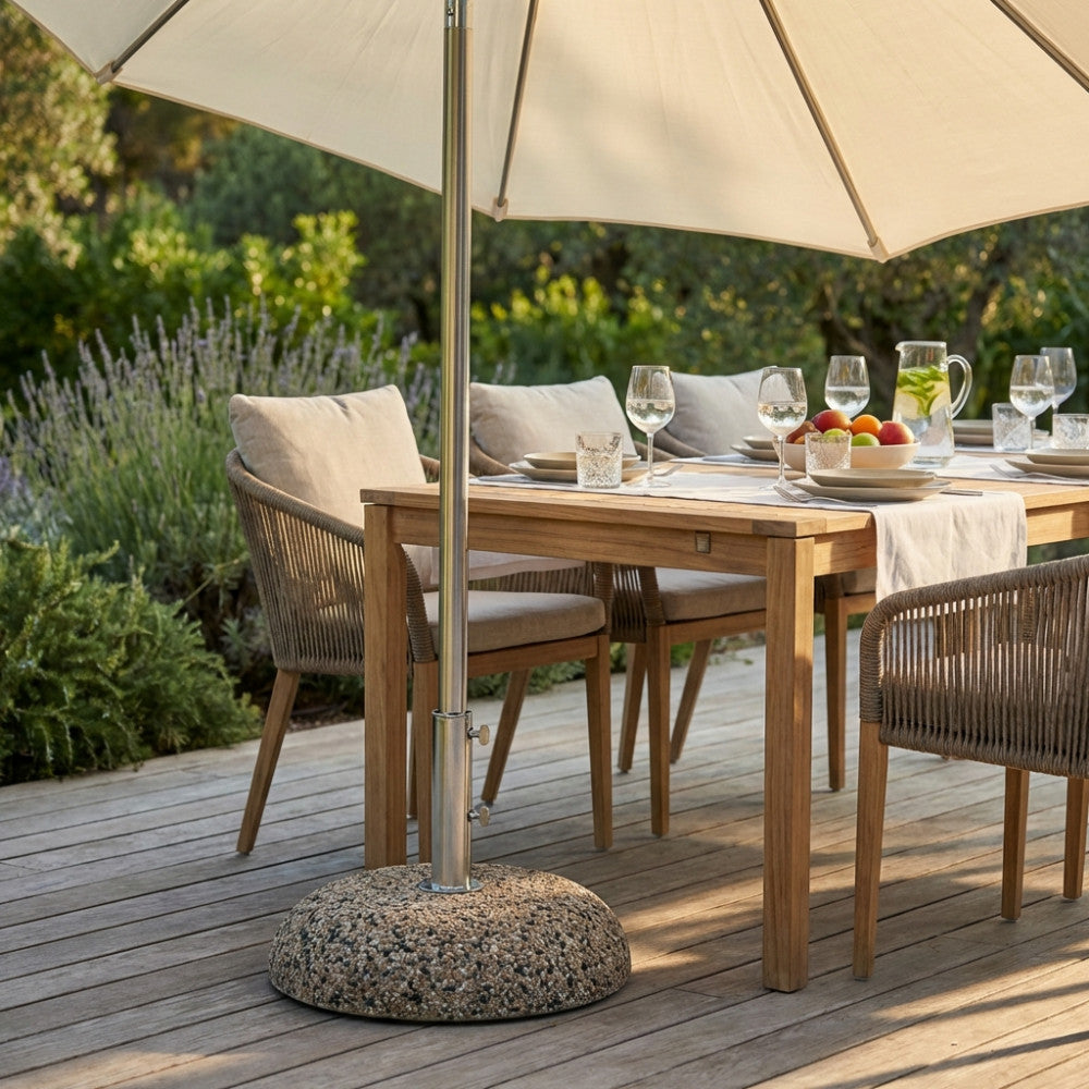 Base per ombrellone in cemento e acciaio posizionata su una terrazza in legno di teak, sotto un tavolo da pranzo all'aperto.