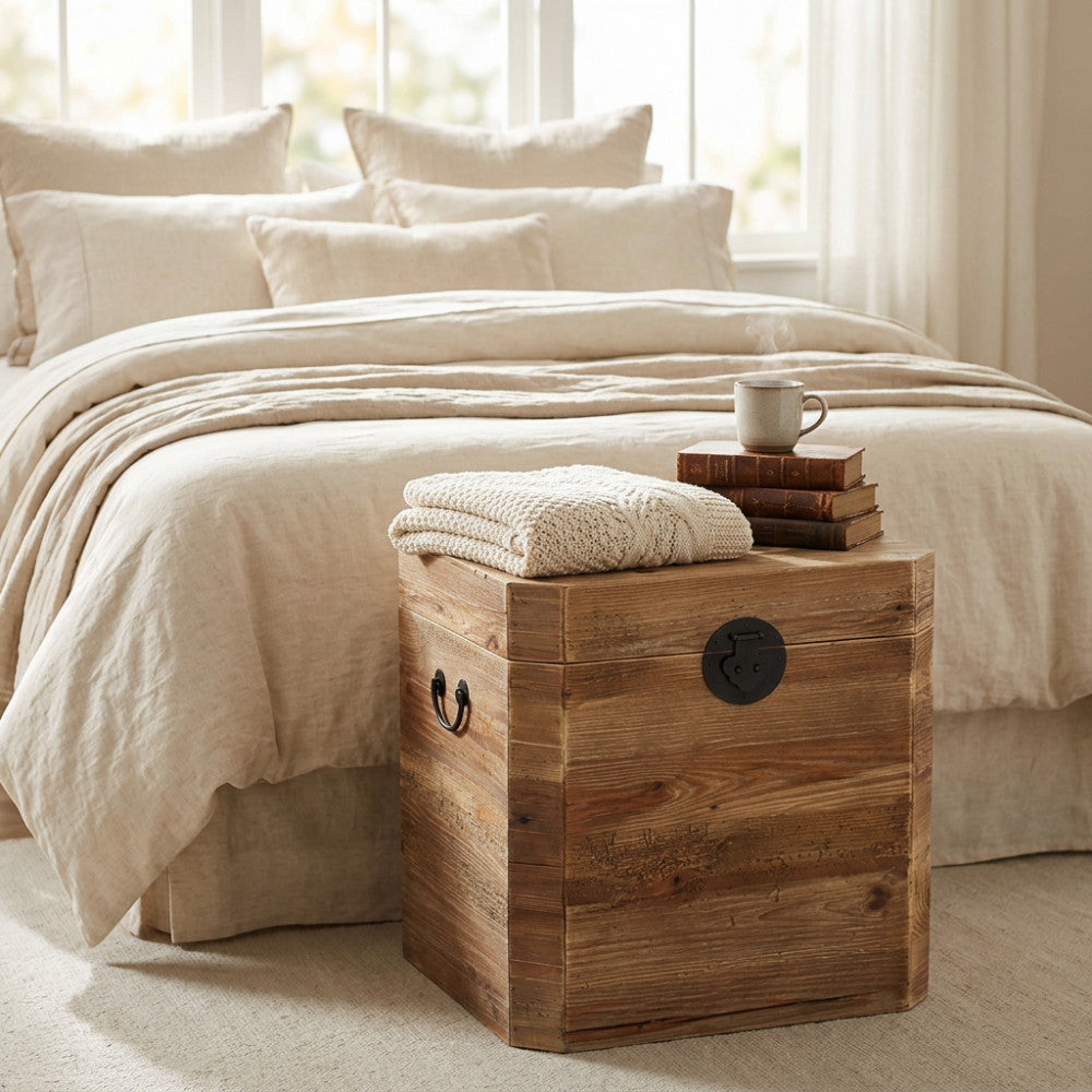 Baule in legno massiccio utilizzato come comodino rustico in una camera da letto luminosa.