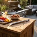 Bruciatore Barbecue Davis appoggiato su un tavolo in legno all'aperto accanto a spiedini freschi e una griglia moderna.