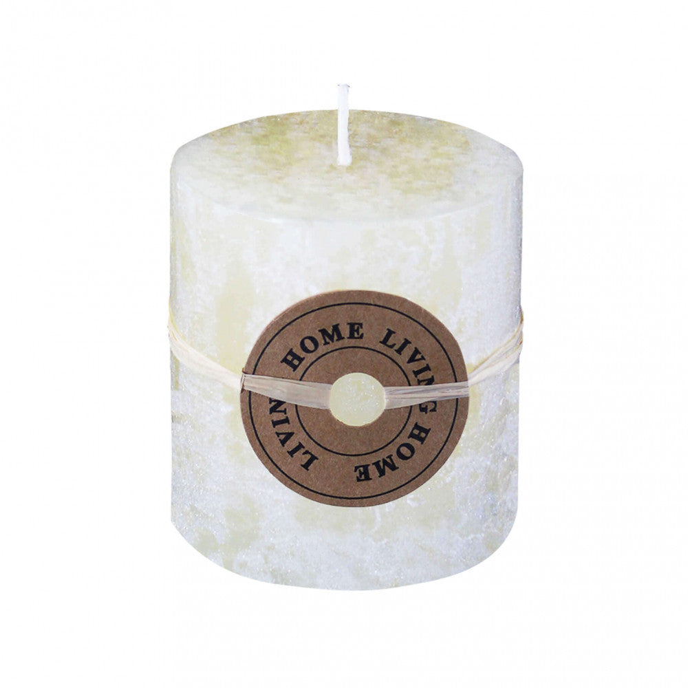 Candela cilindrica profumata di colore avorio con la fiamma accesa, posizionata in un ambiente accogliente.