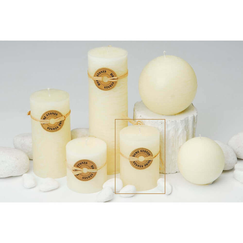 Candela cilindrica profumata di colore avorio con la fiamma accesa, posizionata in un ambiente accogliente.