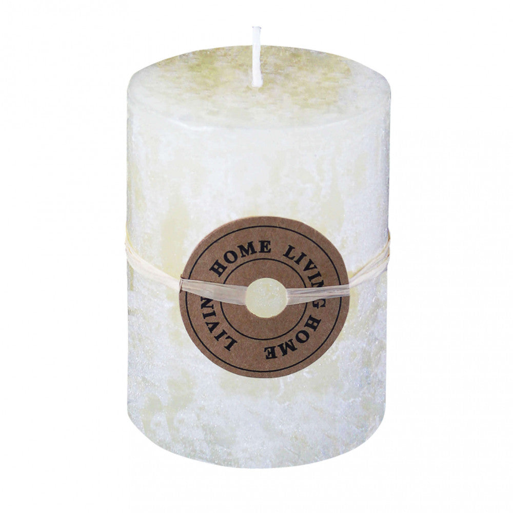 Candela cilindrica profumata di colore avorio con la fiamma accesa, posizionata in un ambiente accogliente.