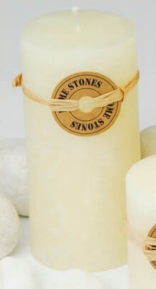 Candela cilindrica profumata di colore avorio con la fiamma accesa, posizionata in un ambiente accogliente.