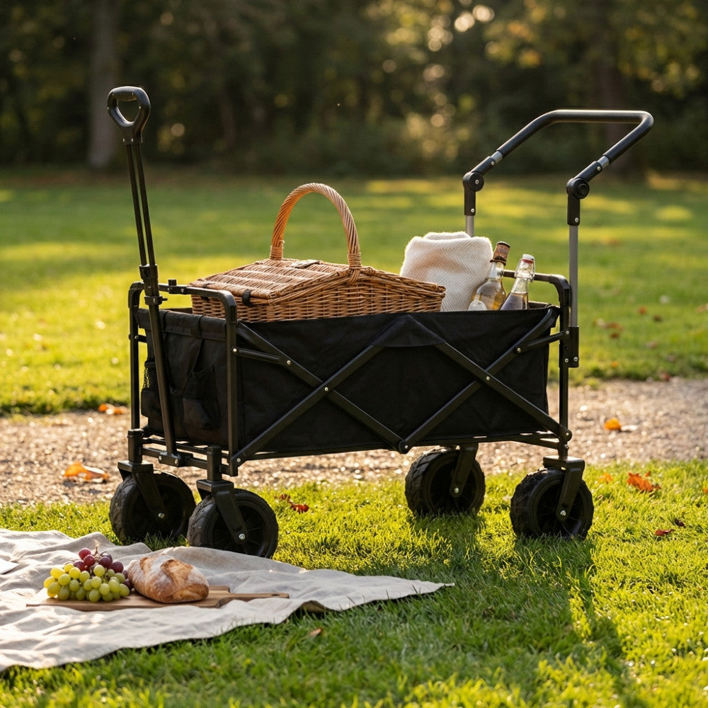 Carrello Artic in metallo antracite posizionato su un prato verde, allestito con un cesto da picnic in vimini e una coperta chiara.