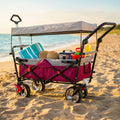 Carrello Baltic in acciaio posizionato su una spiaggia sabbiosa, allestito con asciugamani e accessori estivi sotto la luce naturale.
