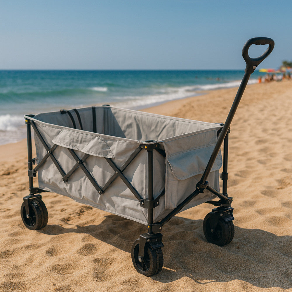 Carrello INDIAN in metallo e poliestere situato su una spiaggia sabbiosa, che illustra la sua versatilità outdoor e le ruote robuste adatte a terreni irregolari.