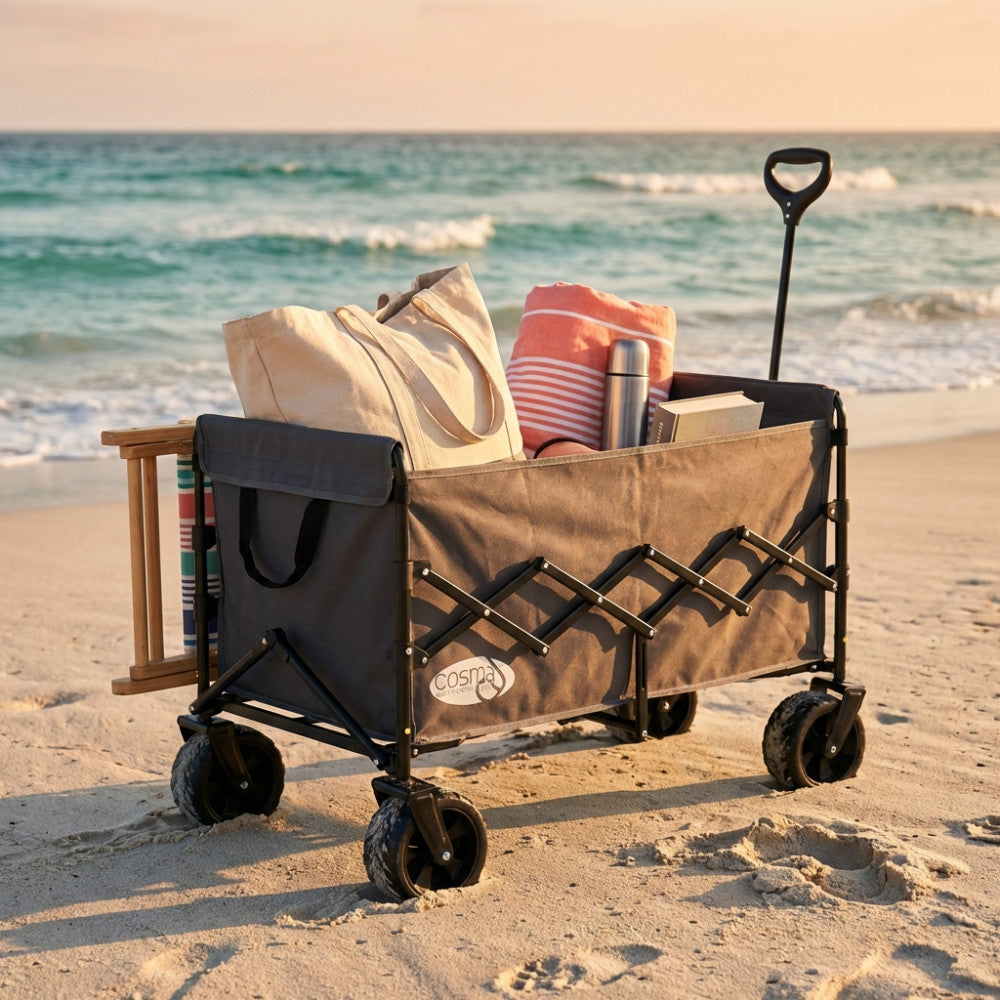 Carrello da esterno North grigio scuro caricato con borse e accessori da spiaggia al tramonto.