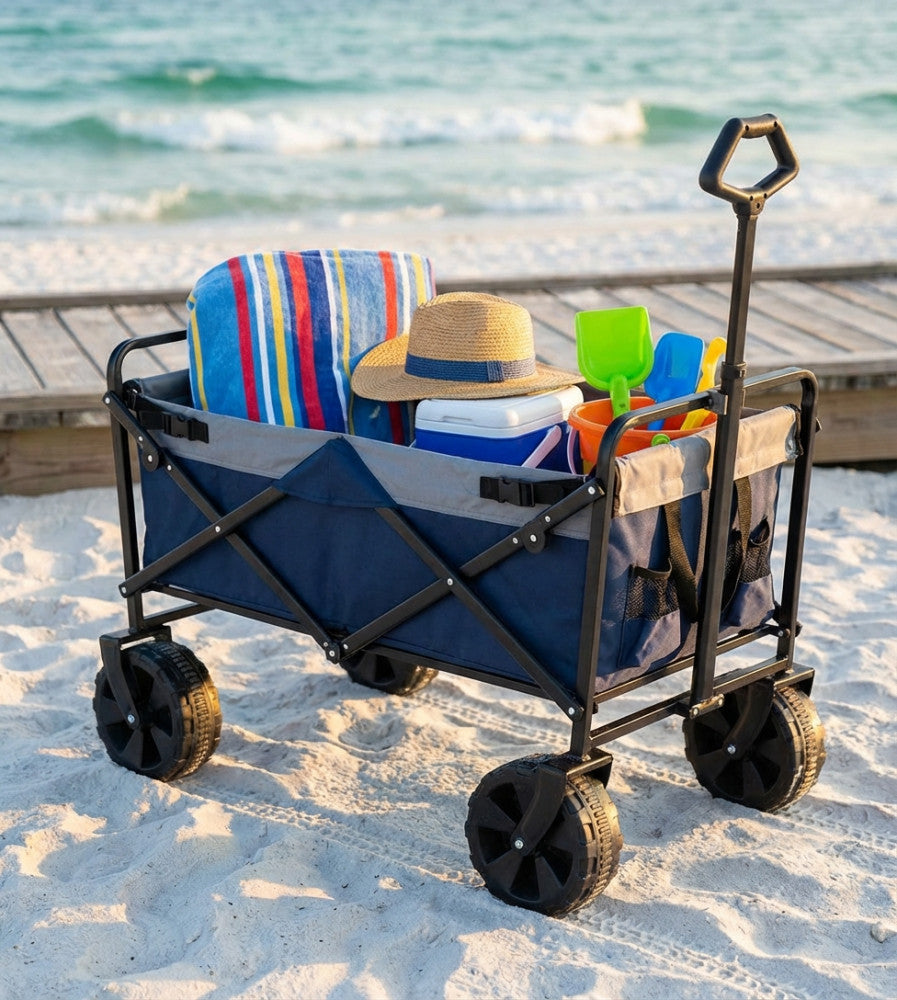 Vista laterale del carrello Pacific blu sulla spiaggia, che mostra le robuste ruote nere e il manico ergonomico.