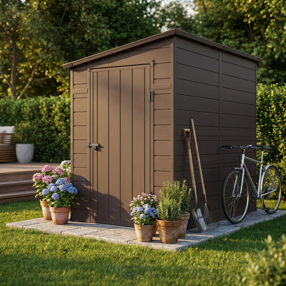 Vista frontale della casetta da giardino marrone con porta chiusa, affiancata da attrezzi agricoli e una bicicletta.