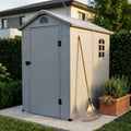Casetta da giardino Home in plastica grigio chiaro, posizionata su lastre di pietra con un rastrello appoggiato e una fioriera in terracotta.