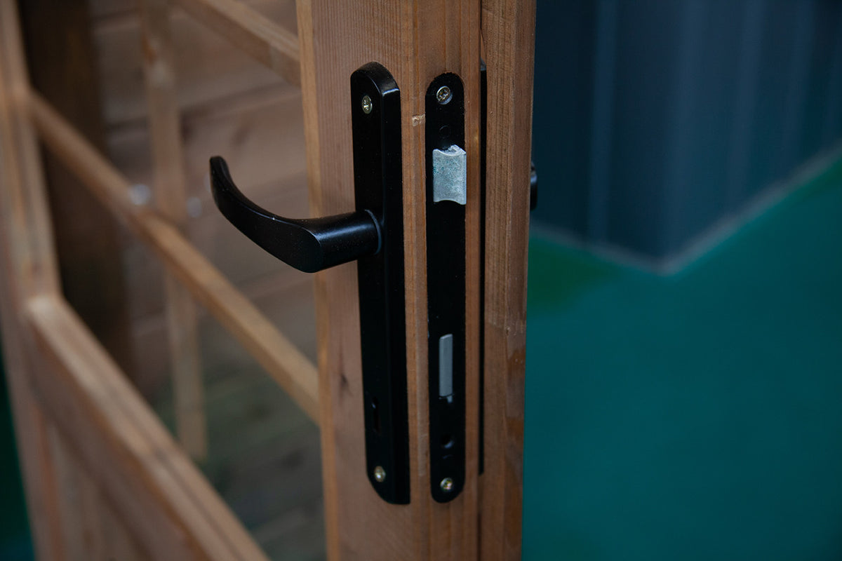 Primo piano della maniglia nera di design e della serratura integrata sulla porta della casetta.