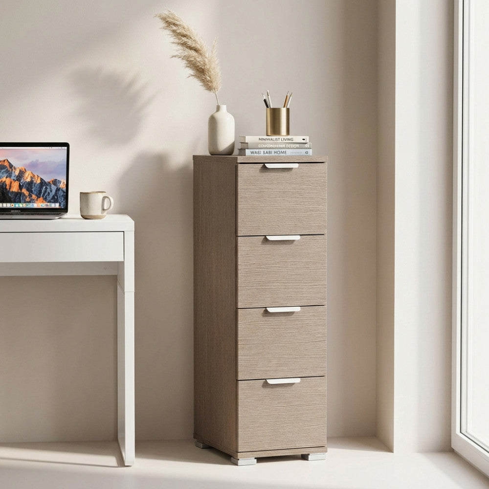 Cassettiera stretta in rovere grigio decorata con vaso e libri accanto a una scrivania bianca.