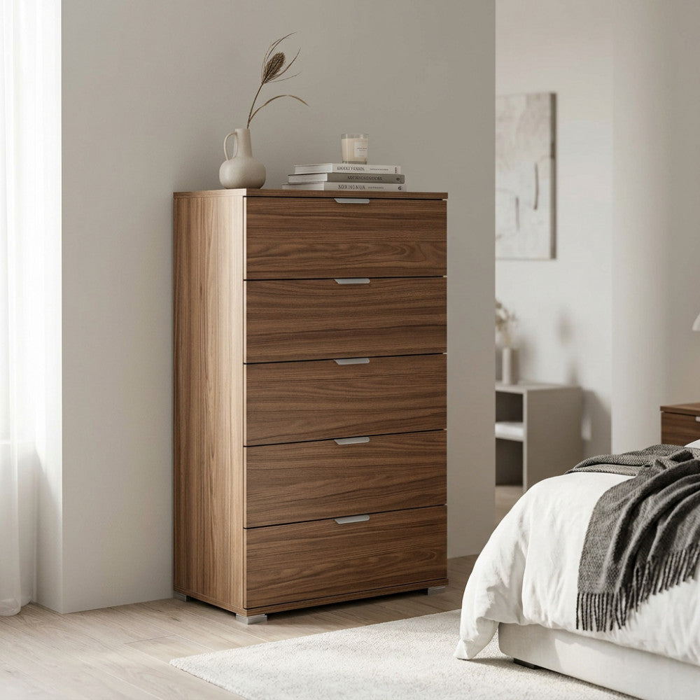 Cassettiera a 5 cassetti color noce ambientata in una camera da letto luminosa con decorazioni minimaliste.