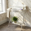 Catino Gilles in acciaio bianco ambientato in un bagno luminoso con carta da parati floreale, asciugamano e pianta decorativa.
