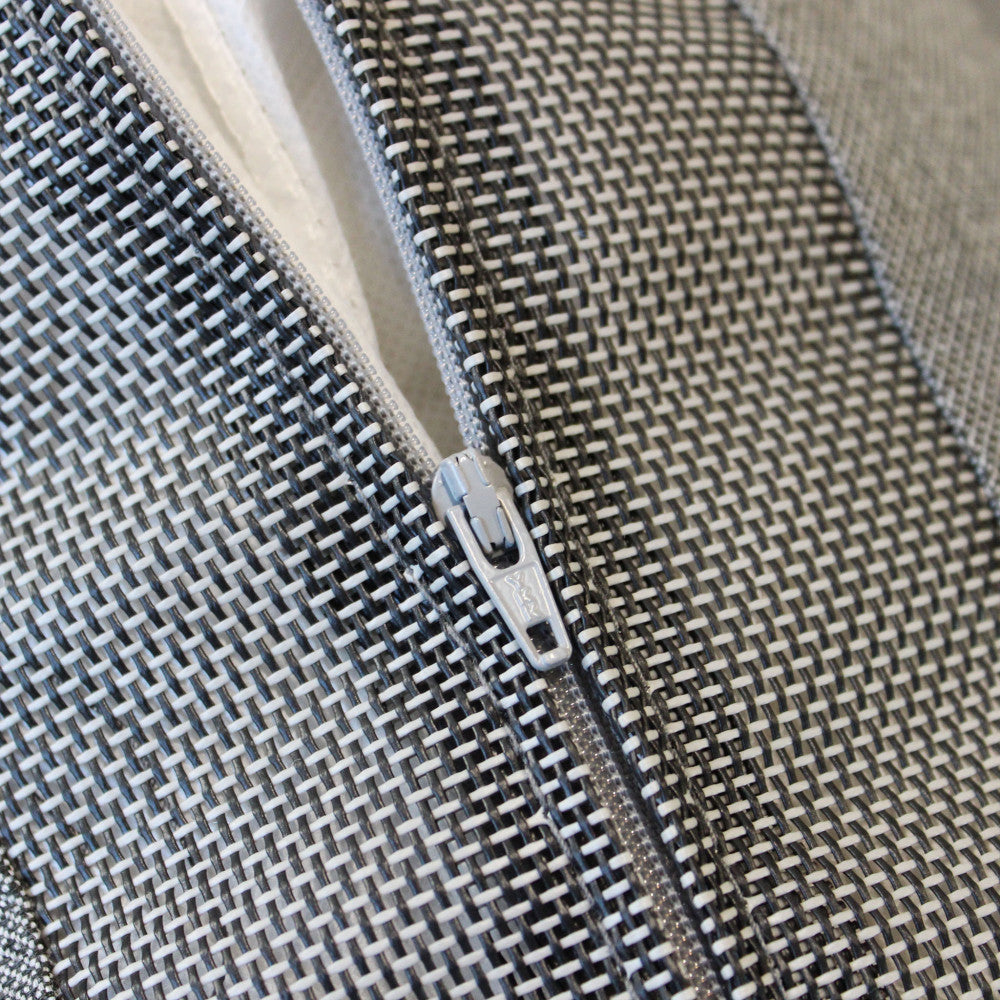 Macro sulla cerniera del cuscino in poliestere grigio, evidenziando la trama del tessuto.