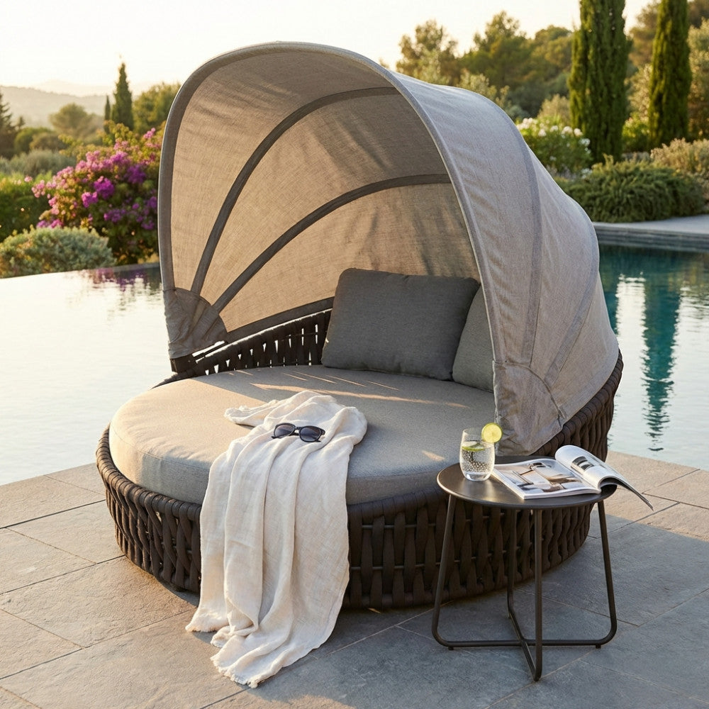 Vista frontale del daybed Camanã in wicker intrecciato con tavolino laterale e bicchiere.