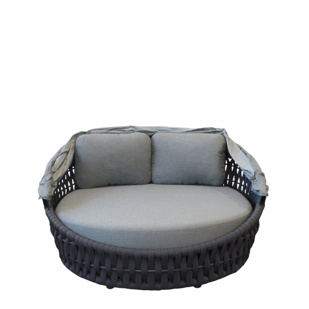 Dettaglio frontale del daybed Camanã con capote ripiegata e cuscineria grigia in evidenza.