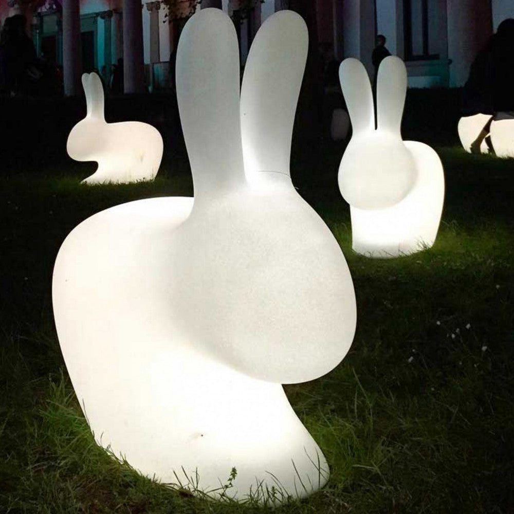 Molteplici sculture luminose Volans in polietilene bianco che illuminano un prato verde durante la notte.