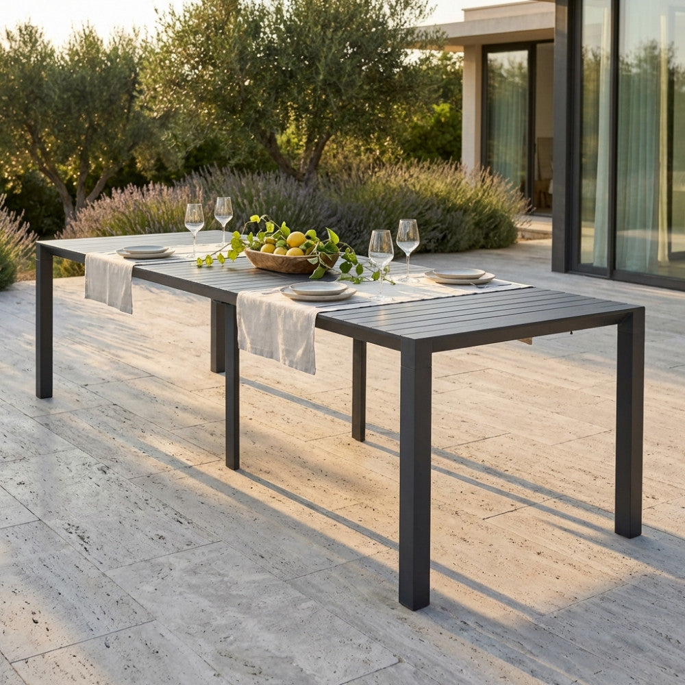 Tavolo consolle estensibile in alluminio antracite allestito per un pranzo all'aperto su una terrazza in pietra.