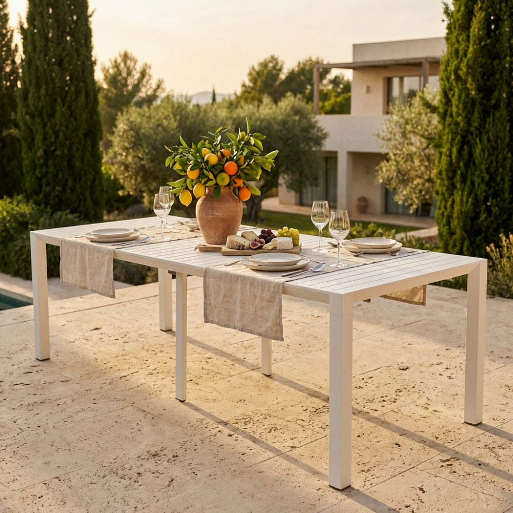 Tavolo consolle estensibile in alluminio bianco allestito per un pranzo all'aperto con decorazioni floreali.