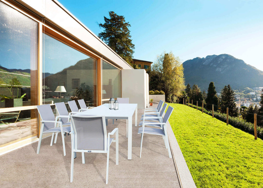 Tavolo da giardino in alluminio bianco abbinato a sedie in textilene su una terrazza panoramica.