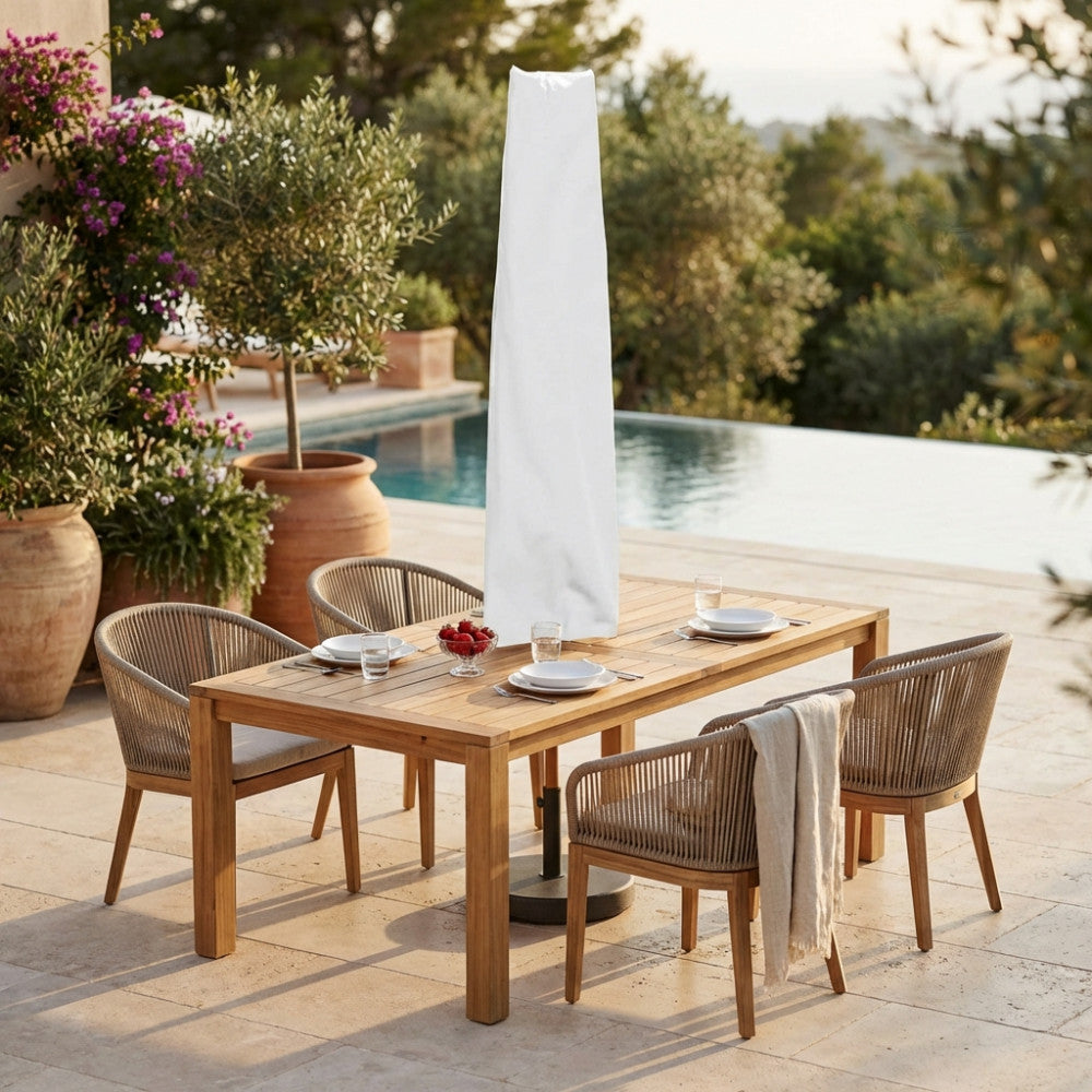 Copertura per ombrellone bianca in poliestere posizionata sopra un tavolo da pranzo in teak a bordo piscina.