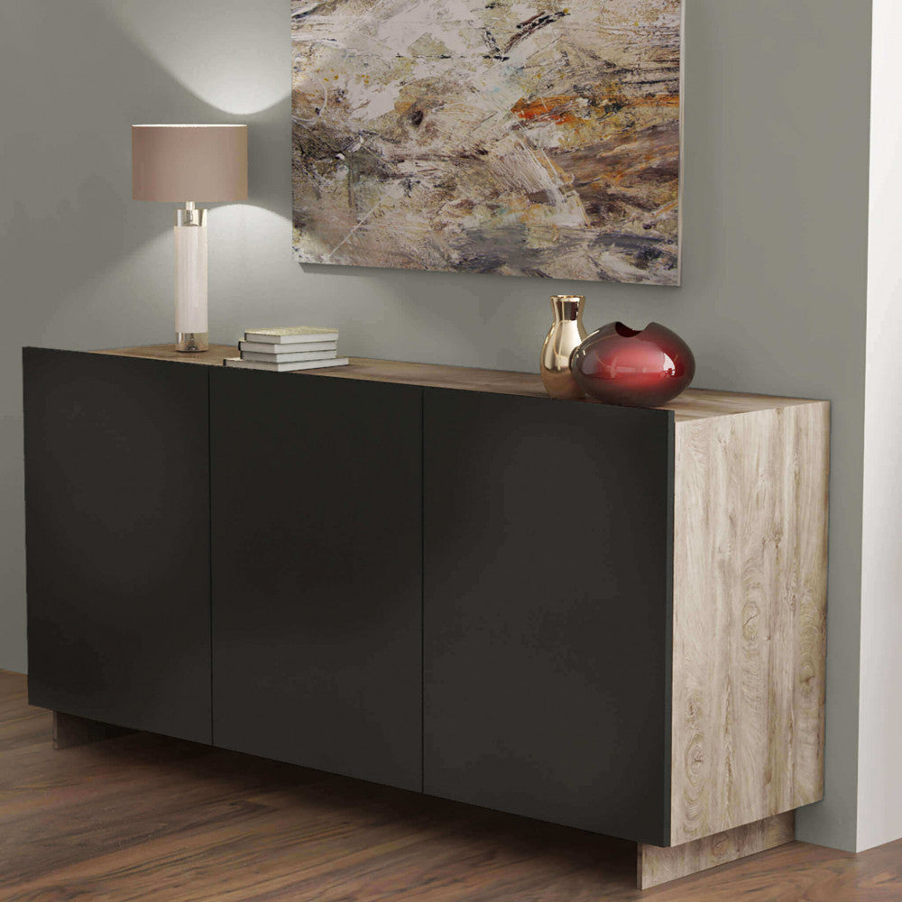 Ambientazione serale della credenza Carlile con lampada da tavolo elegante e vasi decorativi.
