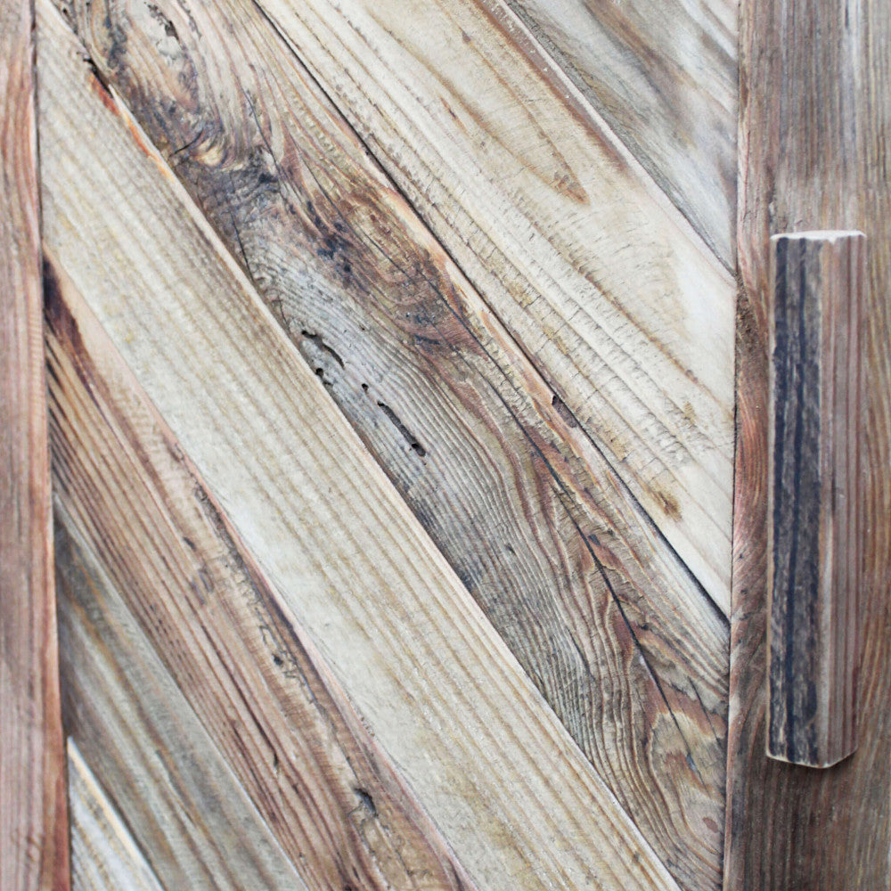 Macro fotografia delle venature del pino riciclato e della maniglia in legno integrata nell'anta della credenza.