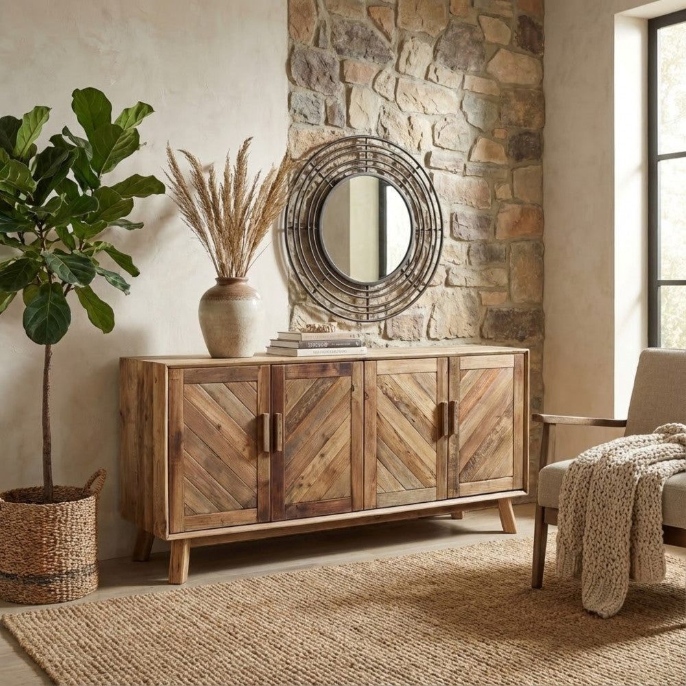 Credenza Roland ambientata in un salotto dal sapore rustico-chic con parete in pietra, specchio rotondo e pianta d'appartamento.