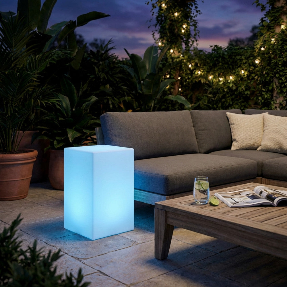 Cubo luminoso Indus con luce LED azzurra in un elegante salotto all'aperto al crepuscolo.