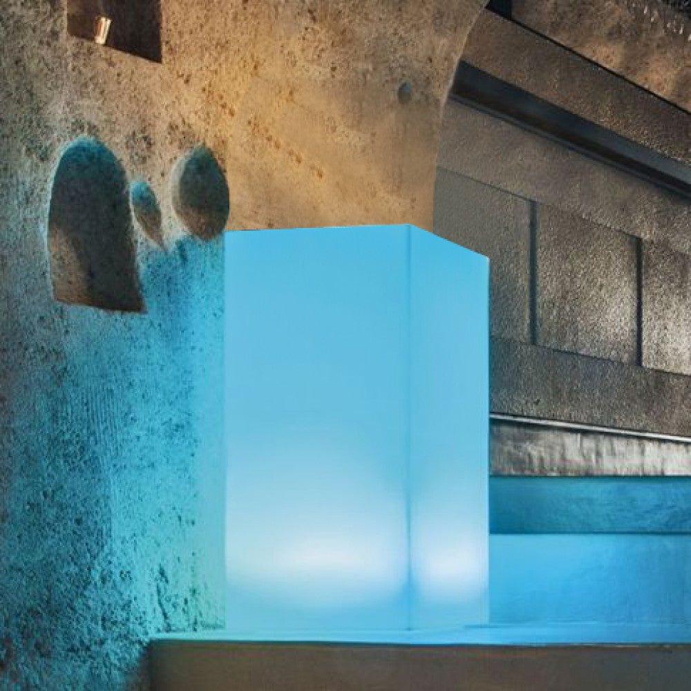 Elemento di illuminazione Cubo Indus con luce blu intensa in un'architettura in pietra.