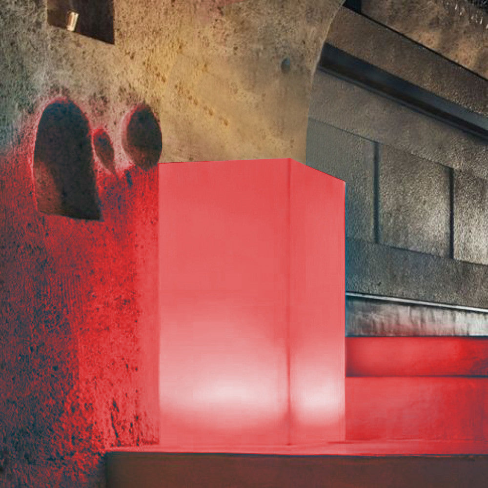 Cubo luminoso Indus acceso con luce rossa vibrante a contrasto con pareti rustiche.