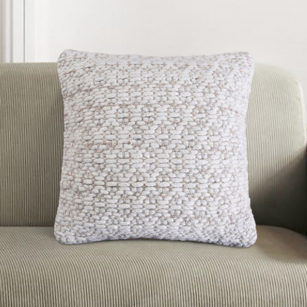 Cuscino Jean bianco ecrù ambientato su una poltrona dal design contemporaneo con texture a coste.