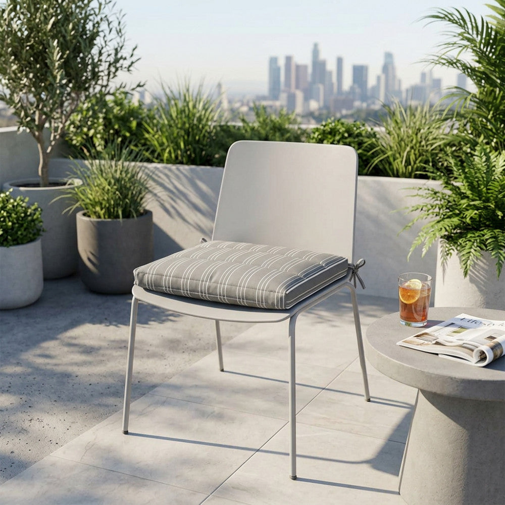 Cuscino da seduta moderno tortora su una sedia grigio chiaro in una terrazza con vista panoramica sulla città.