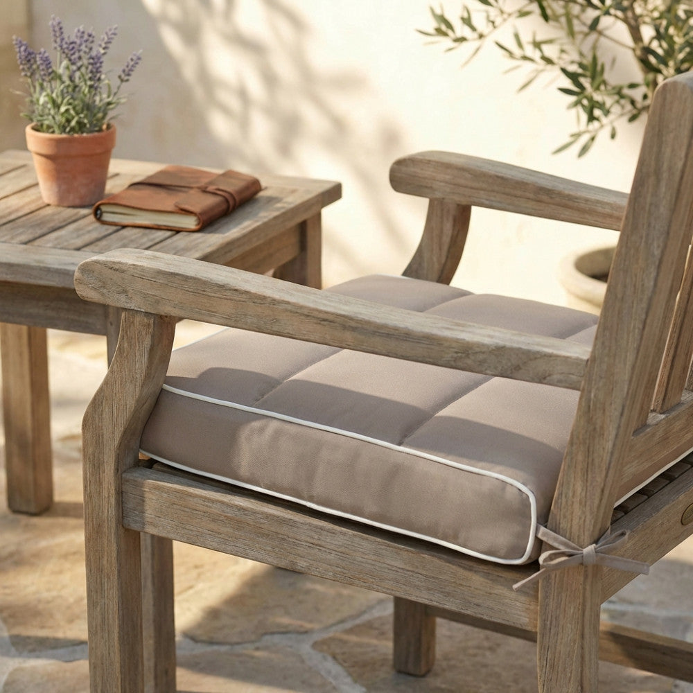 Cuscino seduta color tortora posizionato su una sedia in legno da esterni, illuminato dalla luce naturale.