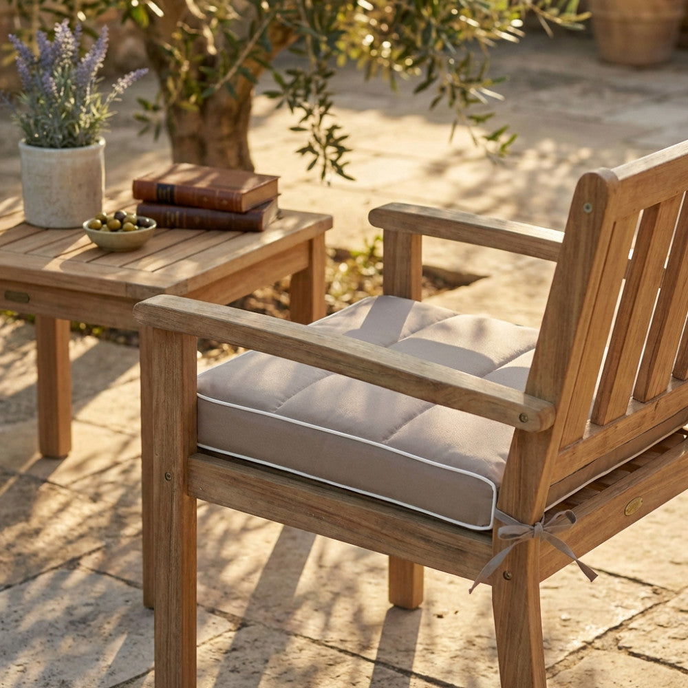 Dettaglio del cuscino in poliestere tortora su sedia in legno, inserito in un elegante contesto giardino.
