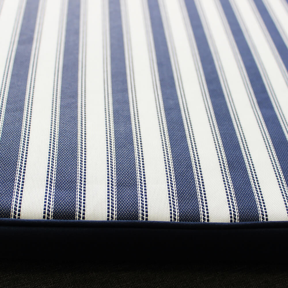 Vista laterale del cuscino Cosma con piping blu