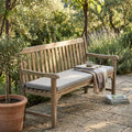 Panca in legno da giardino allestita con il Cuscino Real 110 Righe Tortora, arricchita da una coperta piegata e una tazza.
