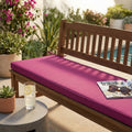 Cuscino magenta Real 150 posizionato su una panca in legno a bordo piscina, decorato con rivista e occhiali da sole.