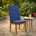 Cuscino Real Alto Blu Scuro posizionato su una sedia in legno di teak in un lussuoso giardino soleggiato.